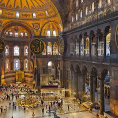 Wnętrze Hagia Sophia z ogromnymi okrągłymi kaligrafiami i turystami.