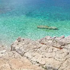 Idealne miejsce, gdzie na wakacje w sierpniu: skalista plaża i krystalicznie czysta, turkusowa woda.