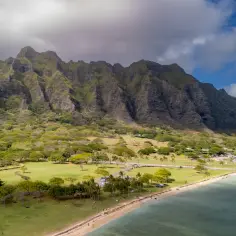 Majestatyczne góry Ko'olau górują nad zielonymi polami i plażą, przypominającymi krajobraz z **Waikiki**.