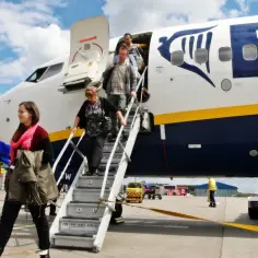 Maskotka wita pasażerów schodzących po schodkach samolotu Ryanair, hiszpańskie linie lotnicze.