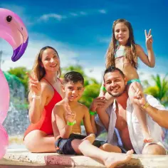Rodzina z dmuchanym flamingiem cieszy się słońcem i wodą. Idealne miejsce, gdzie na wakacje z dziećmi.