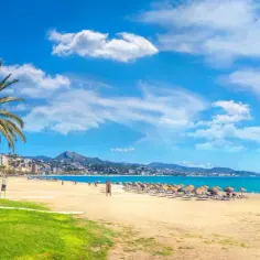 Malaga plaże: palmy, złoty piasek, turkusowe morze i miasto w tle. Idealne miejsce na wakacje.