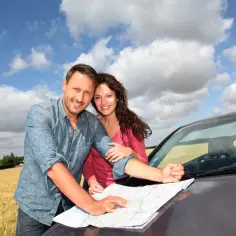 Para planowania podróży za granicę krótkoterminowe, para z mapą przy samochodzie w słoneczny dzień.