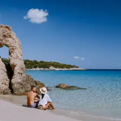 Para na plaży na Sardynii, majowa pogoda idealna na relaks przy krystalicznie czystej wodzie i skalnych formacjach.