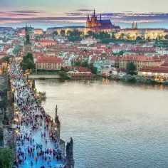 Tłum ludzi na Moście Karola w Pradze. W tle widać panoramę miasta i zamek. Ceny w Czechach mogą być różne, ale widok jest bezcenny.