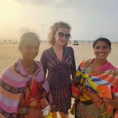 Trzy kobiety na plaży. Jedna w okularach, dwie w kolorowych szalach. Może sprzedają coś za rupie?