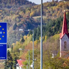 Granica Słowacji i Polski. Winiety na autostrady są obowiązkowe. W tle jesienne drzewa i kościół.