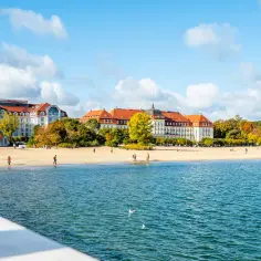 Piękne miejscowości nad morzem jesienią. Plaża i hotele w Sopocie, z ludźmi spacerującymi po piasku.