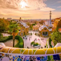 Park Güell w Barcelonie, jedno z najpiękniejszych miast w Hiszpanii, zachwyca mozaikową ławką i bajkowymi budynkami o zachodzie słońca.