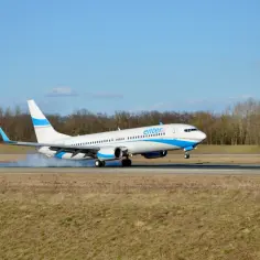 Samolot Enter Air ląduje na pasie startowym, unosząc tumany kurzu.