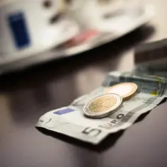 Na stole leży banknot 5 euro i dwie monety. To waluta w Grecji, idealna na kawę i ciastko.