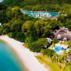Rajskie wakacje w Malezji: tropikalna plaża, turkusowa woda, luksusowy resort z basenem i jachty w zatoce.