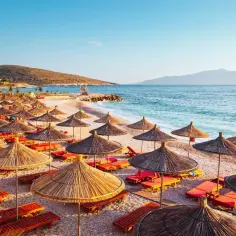 Albania pogoda wrzesień: pusta plaża z leżakami i parasolami pod błękitnym niebem, idealna na relaks.