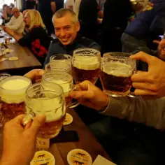 Ludzie wznoszą toasty kuflami piwa w czeskim pubie. Zastanawiasz się, ile kosztuje piwo w Czechach?