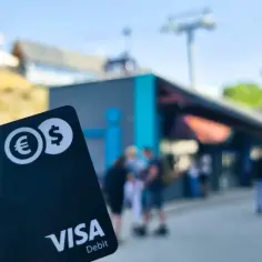 Karta wielowalutowa Visa Debit z symbolami euro i dolara, gotowa na podróż.