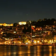 Oświetlone miasto na wzgórzu, z zamkiem i flagą Macedonii, nocą. Idealne miejsce na wakacje w Macedonii.