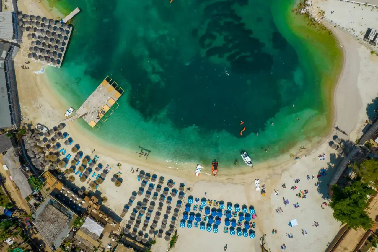 Albania, wrzesień: słoneczna pogoda na plaży z turkusową wodą, leżakami i parasolami. Idealne warunki do wypoczynku.