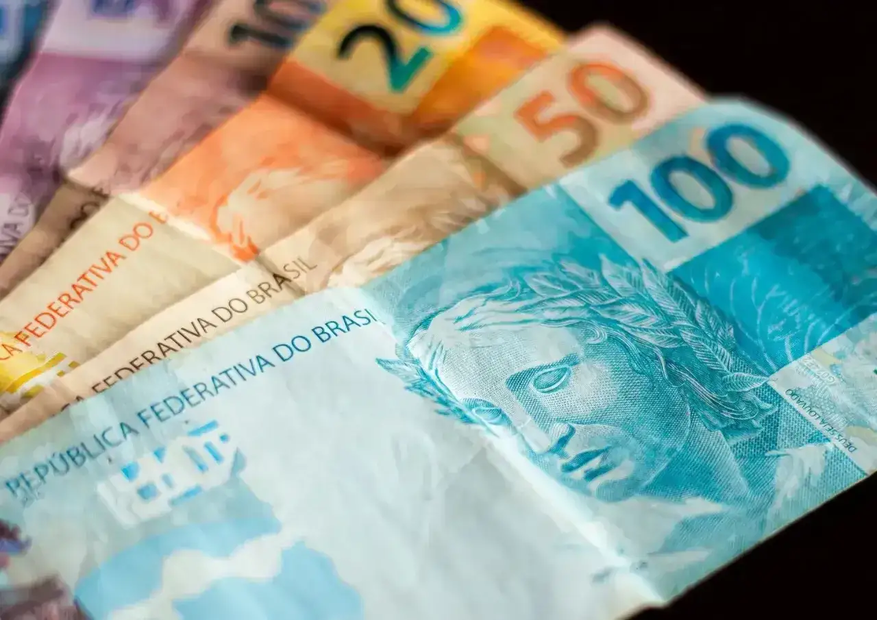 Różne banknoty, w tym 100, 50 i 20, tworzą wachlarz. To waluta Brazylii, real brazylijski, z wizerunkiem kobiety na banknocie 100.