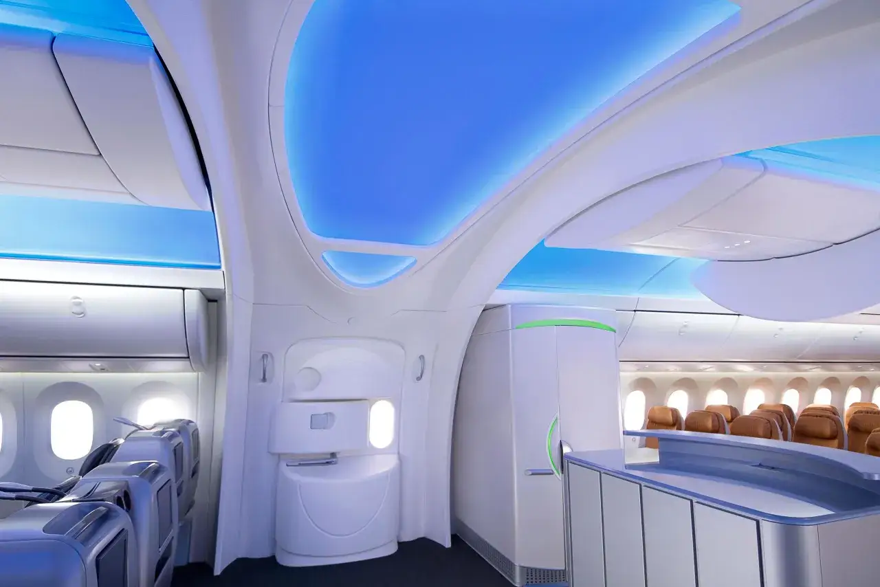 Nowoczesne wnętrze samolotu Boeing 787 z niebieskim podświetleniem sufitu i wygodnymi fotelami.