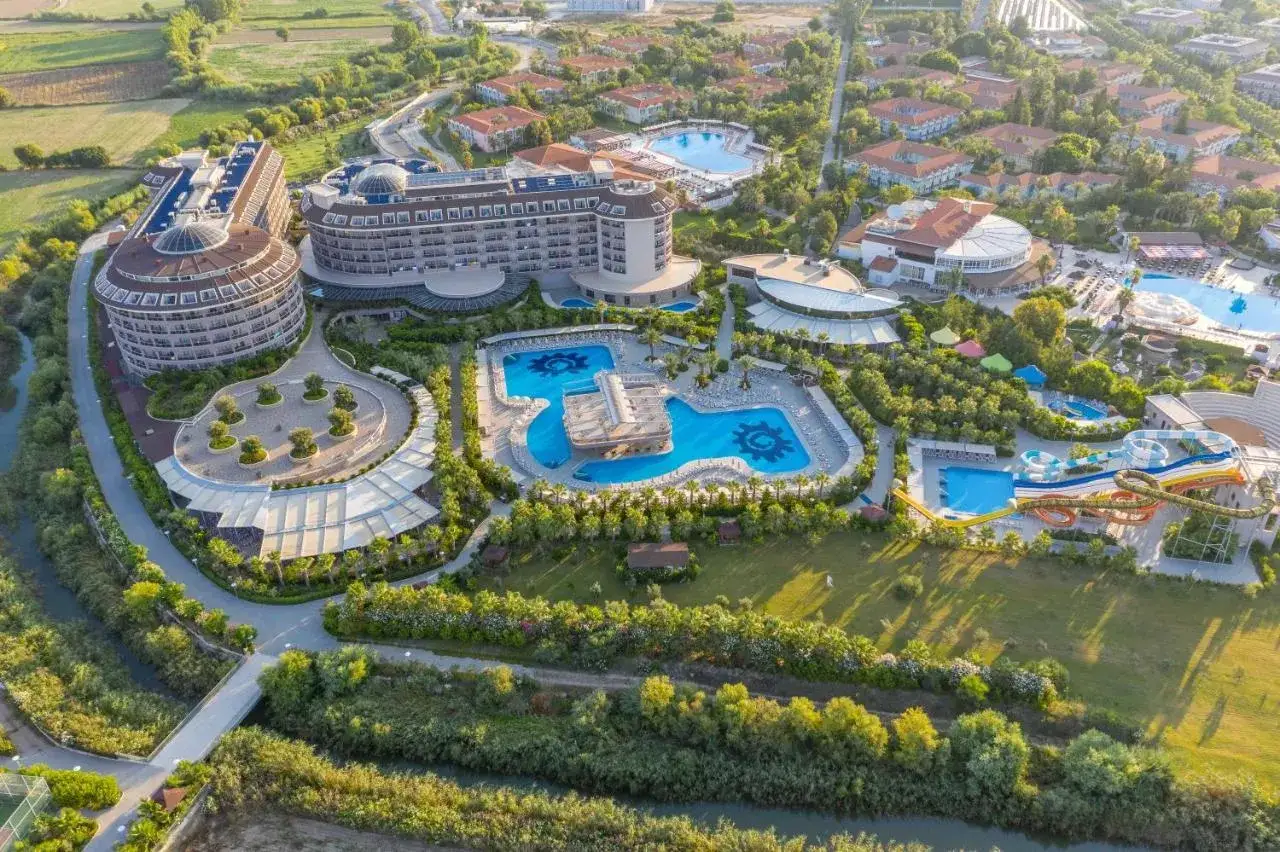 Kompleks hotelowy Kizilagac z basenami, zjeżdżalniami wodnymi i bujną zielenią, otoczony rzeką i polami.