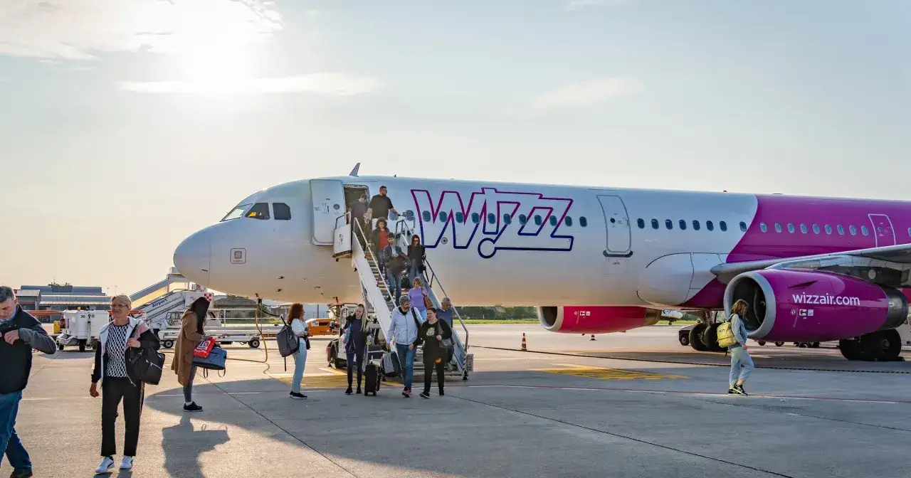 Pasażerowie schodzą po schodkach z samolotu Wizz Air. Wizz priority dla wszystkich podróżnych.