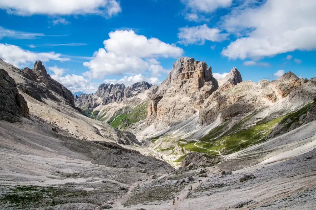 Malownicze Val di Fassa w Dolomitach. Kręta ścieżka prowadzi przez skaliste zbocza i zielone hale ku majestatycznym szczytom.