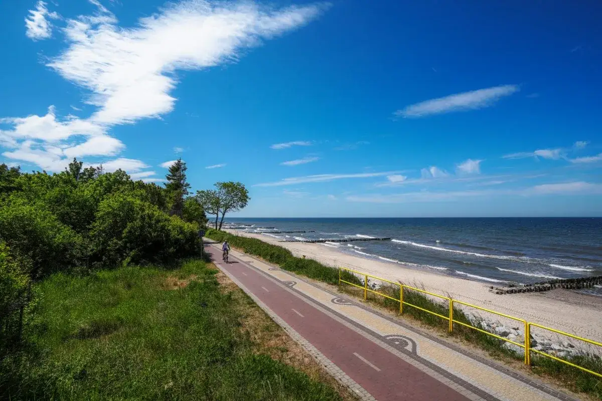 Piękna ścieżka rowerowa wzdłuż plaży, idealna dla miłośników aktywnego wypoczynku w nadmorskich miejscowościach.