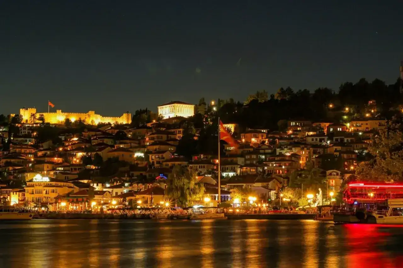 Oświetlone miasto na wzgórzu, z zamkiem i flagą Macedonii, nocą. Idealne miejsce na wakacje w Macedonii.