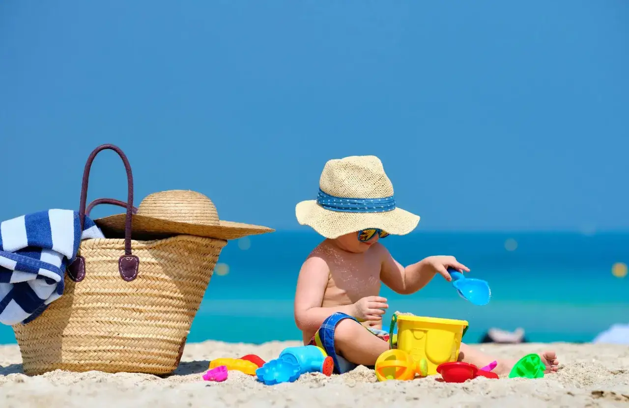 Słońce, plaża i zabawki - idealne wakacje nad morzem z dzieckiem! Pamiętaj o kapeluszu i torbie plażowej.