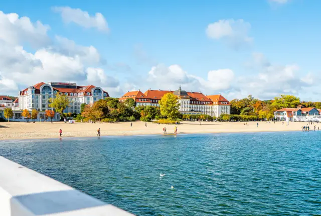 Piękne miejscowości nad morzem jesienią. Plaża i hotele w Sopocie, z ludźmi spacerującymi po piasku.